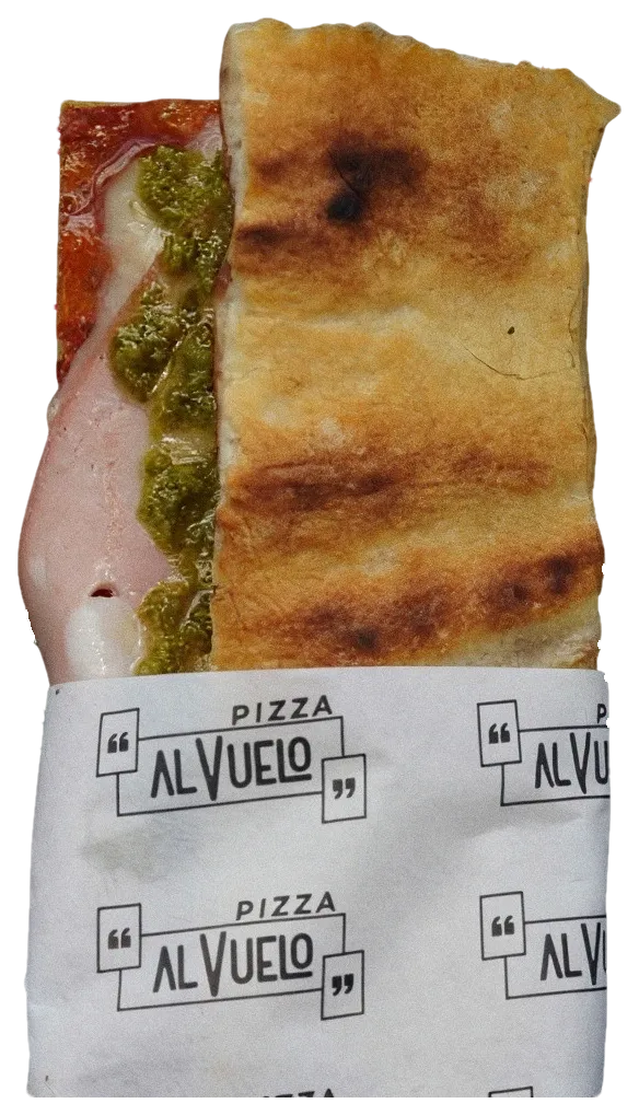 Pizzetta Mortadella & Pesto doblada en su papel, con la mortadella y el pesto a la vista.